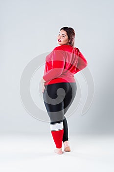 Plus size model in sportswear, fat woman on gray background, healthy lifestyle concept