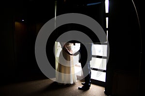Plus size wedding couple is hugging near the window. Bride in puffy dress and groom silhouettes on wedding day photoshoot