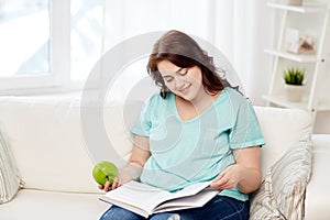 Plus size woman with book and apple at home
