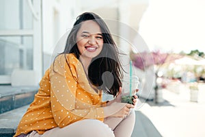 Plus size woman drinking spinach smoothie while walking the city street