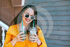 Plus size woman drinking take away cocktail over city cafe wall