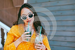 Plus size woman drinking take away cocktail over city cafe wall