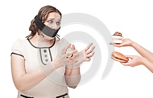 Plus size woman gagged stretching hands to junk food