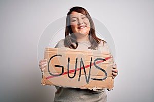 Plus size woman holding stop guns cardboard banner warning about violence with a happy face standing and smiling with a confident