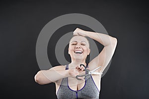 Plus size woman shows her hairy armpit. the girl holds a pair of scissors in her hand and feels joyous surprised emotions, she
