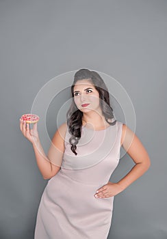 Plus size woman thinking about eating donut. Overweight concept