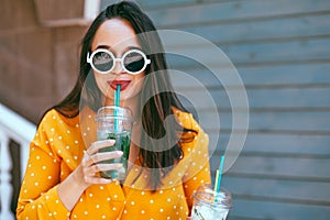 Plus size woman drinking take away cocktail over city cafe wall