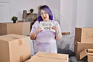 Plus size woman wit purple hair moving to a new home holding banner clueless and confused expression