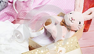 Plush baby toy rabbit for a newborn with toys, top view on a pink wooden background