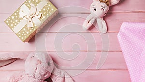 Plush baby toy rabbit for a newborn with toys, top view on a pink wooden background