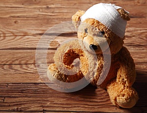 Plush Brown Teddy Bear with Bandaged on the Table