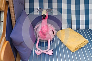 Plush flamingo takes a sunbath in a beach chair.