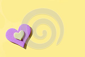 Plush heart shape in yellow and pink on a yellow background. Harsh lighting and hard shadows enhance pop art style. Copy space