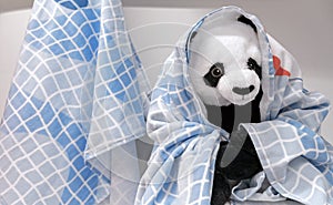 Plush panda toy wrapped in a baby bath towel