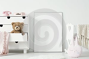 Plush toy in cabinet next to poster with mockup and cradle in ba photo