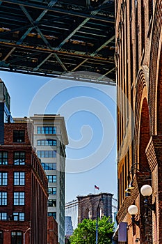 Plymouth St under Manhattan Bridge with view on element of Brooklyn Bridge with Amerian flag