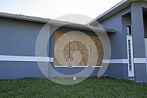 Plywood mounted as storm shutters for hurricane protection of house windows. Protective measures before natural disaster