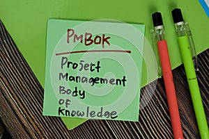 PMBOK - Project Management Body of Knowledge write on sticky notes isolated on Wooden Table. Business of Finacial concept