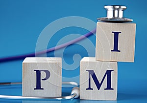 PMI - acronym on wooden large cubes on blue background with stethoscope photo