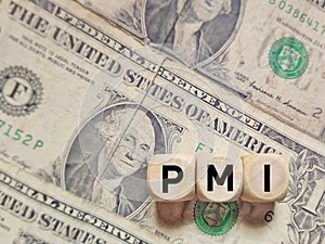 PMI text on wooden cubes with banknote background. Business concept. photo