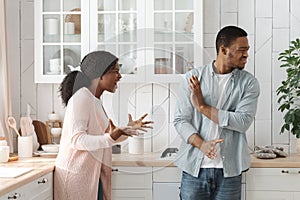 PMS Concept. Furious Young African American Woman Screaming At Husband In Kitchen