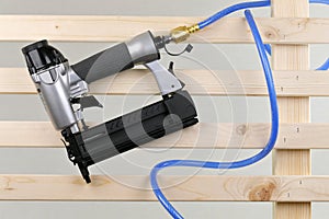 Pneumatic nailer and pressure hose isolated on a wooden paling