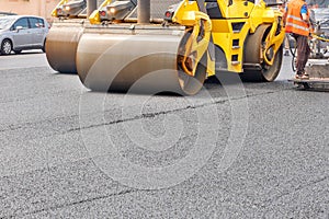 Pneumatic steam road rollers compact fresh asphalt on the road in front of a construction site