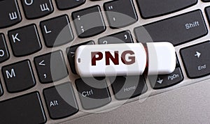 PNG - the word on a white flash drive, lying on a black laptop keyboard