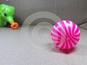 A pnik and white ball on the surface and green elephant toy photo