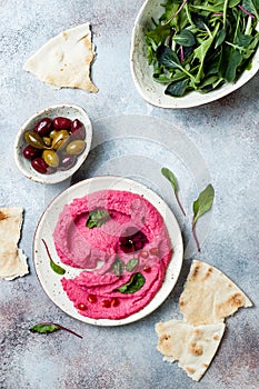 Pnk beet hummus spread or dip with mix salad leaves. Healthy raw summer appetizer, vegan, vegetarian snack.