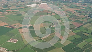 The Po Valley in Italy from the plane window during the landing of the airplane. Agricultural fields with green and brown colors