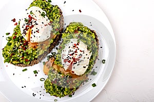 Poached eggs with avocado guacomole on brown bread with sesame seeds. Healthy breakfast on a white background.