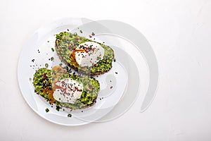 Poached eggs with avocado guacomole on brown bread with sesame seeds. Healthy breakfast on a white background. Copy