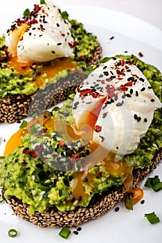 Poached eggs with avocado guacomole on brown bread with sesame seeds. Healthy breakfast on a white background.