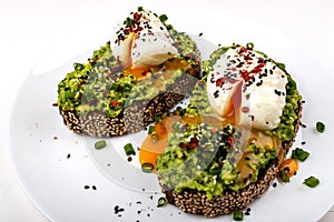 Poached eggs with avocado guacomole on brown bread with sesame seeds. Healthy breakfast on a white background.