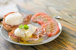 Poached eggs served on toast with bacon and tomato and herbs