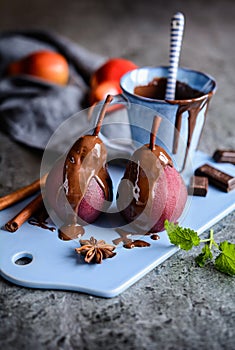 Poached pears in red wine and topped with chocolate sauce