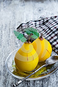 Poached pears with spices in a serving dish on wooden table