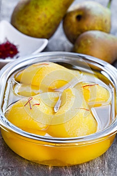 Poached pears with spices in syrup on the glass bowl