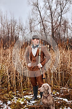 Poacher with dog in Forest. Man holding shotgun. Hunter man. Hunting period, autumn season.