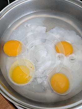 Poaching fresh eggs in a pan of water. photo
