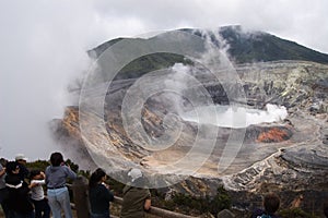 Aerial view of Poas Volcano. Group of tourists looking at its crater while smoke comes out