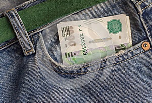 In a pocket of blue jeans there is a paper thousandth bill. Money, budget, income, expenses, finance and economics