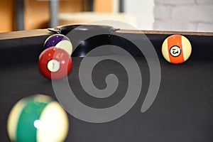 The pocket or hole of a billiard table that is covered with black billiard cloth balls are out of focus. The pocket is protected
