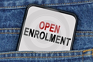 In a pocket of jeans there is a smartphone on the screen of which the text - OPEN ENROLMENT