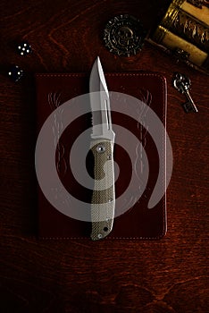 Pocket knife on leather book with pirate gold