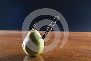 Pocket knife nailed to a green pear