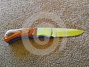 Pocket knife with wooden handle, open, placed on brown terry cloth