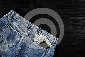 Pocket money. Dollar in hip pocket of worn blue jeans. Close-up.