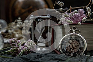 Pocket watch, blur stack of old book, hourglass, vintage binocular and world desk globe on dark background